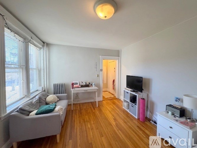 A living room with a grey couch, a white coffee table, a television, and a printer on a white cabinet.