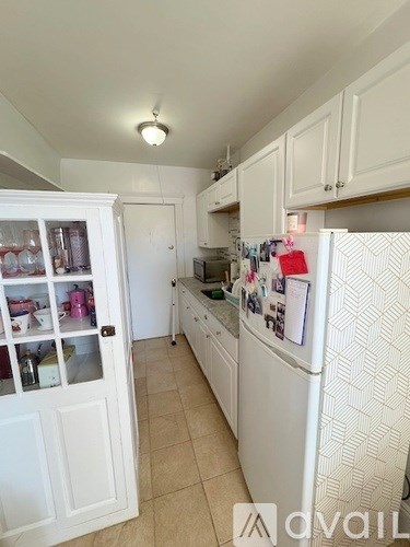 A kitchen with white cabinets and a white fridge.