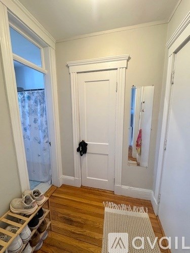 A hallway with a white door and a pair of shoes on the floor.