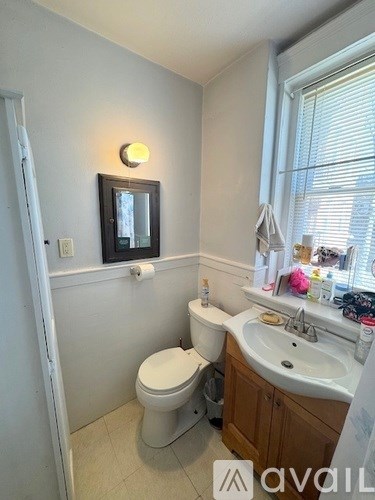 A bathroom with a toilet, sink, and mirror.