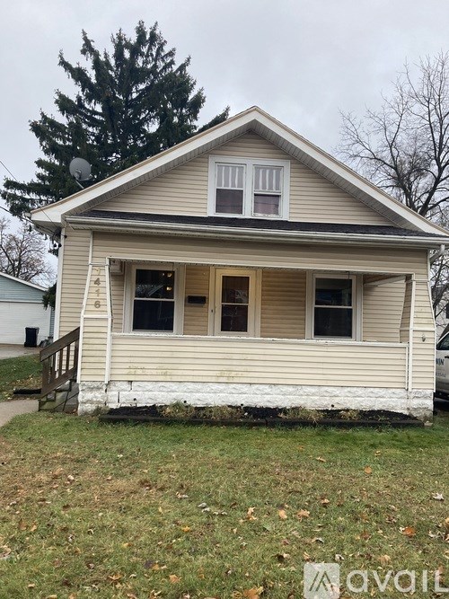 A small, two-story house with a porch and a satellite dish on the roof.