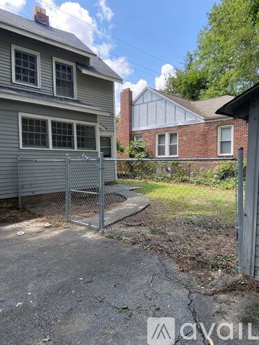 A grey house with a metal fence in front of it.