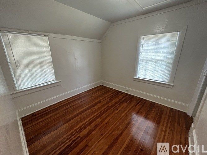 A room with wooden floors and two windows.