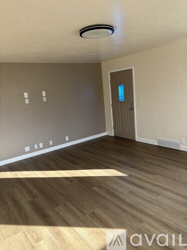 A room with a wooden floor and a door with a blue light on it.