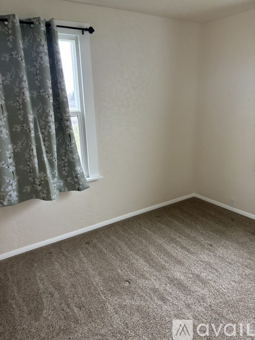 A room with a carpeted floor and a window with curtains.