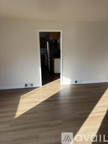 A room with wooden flooring and a doorway leading to another room.