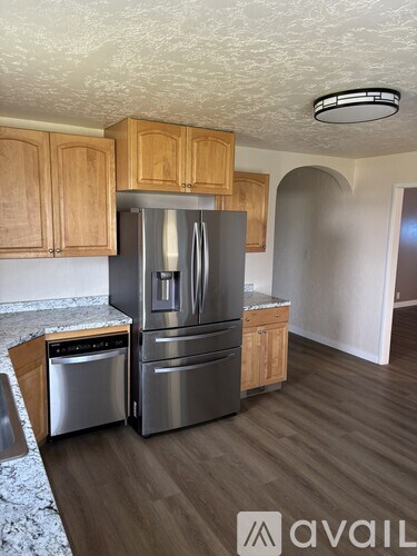 A kitchen with a stainless steel refrigerator and wooden cabinets.