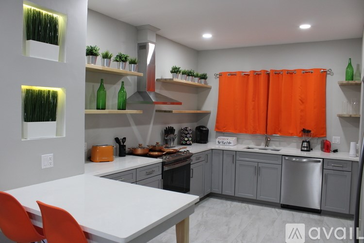 A kitchen with a white table and orange chairs.