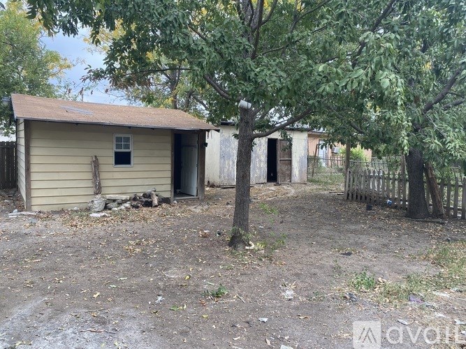 A small, dilapidated house with a tree in front.