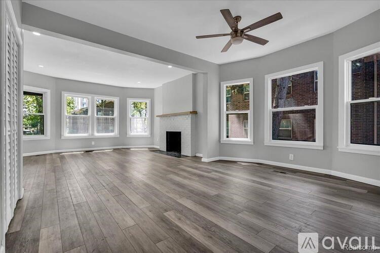 A spacious room with wooden flooring and a ceiling fan.
