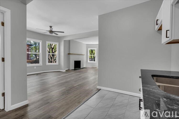 A spacious living room with a ceiling fan and hardwood flooring.