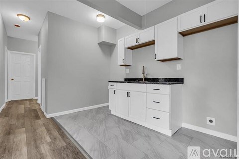 A kitchen with white cabinets and a black countertop.