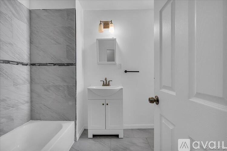 A white bathroom with a marble wall and a white sink cabinet.