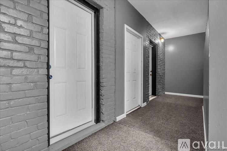 A hallway with a white door on the left and a carpeted floor.