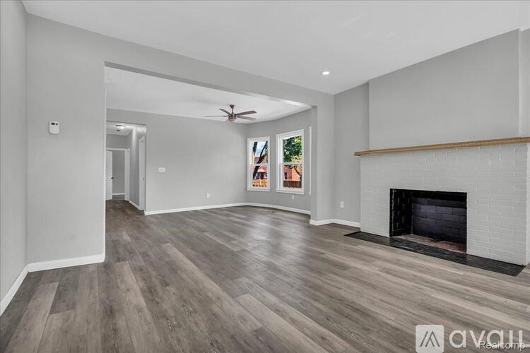 A spacious living room with a fireplace and a ceiling fan.