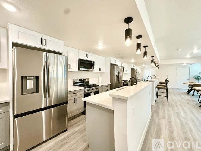 A modern kitchen with a stainless steel refrigerator and white cabinets.