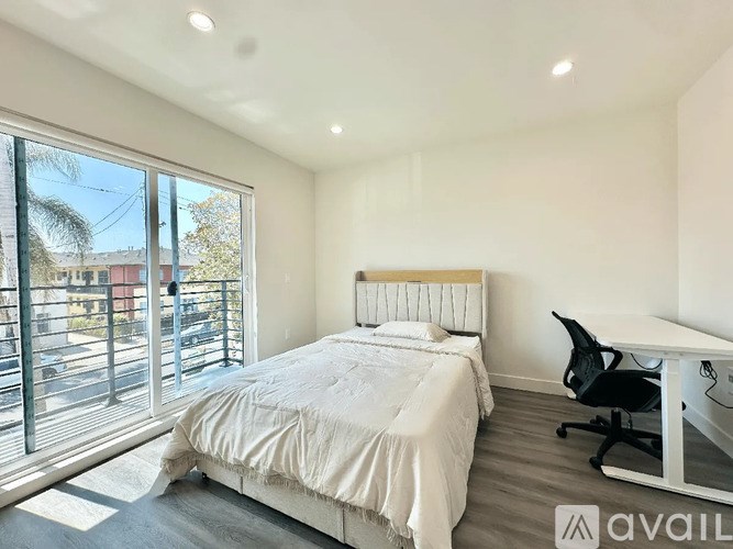 A bedroom with a large bed, desk, and chair.