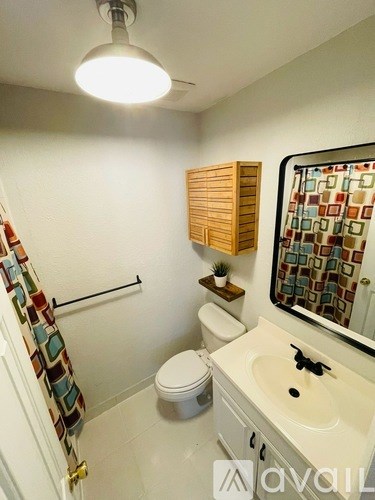 A bathroom with a toilet, sink, and a shower curtain.
