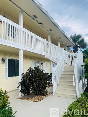 A white balcony with a staircase leading to a house.