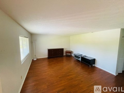 A living room with a brown sofa and a black ottoman.