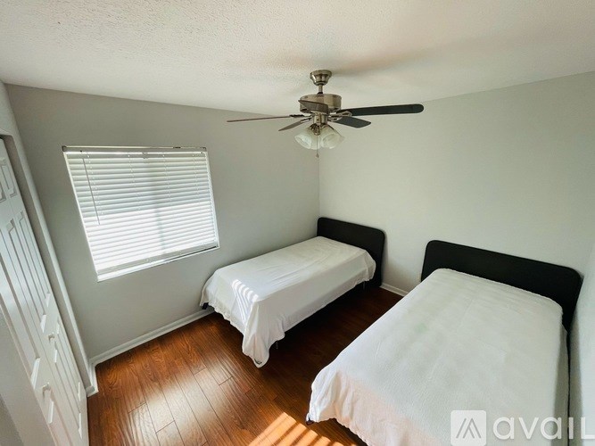 Two twin beds in a room with a ceiling fan.