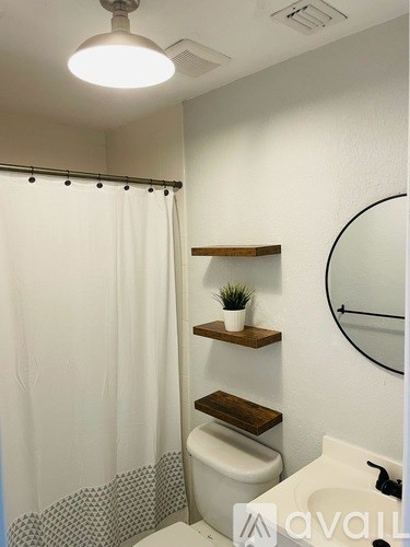 A bathroom with a white shower curtain and a round mirror.