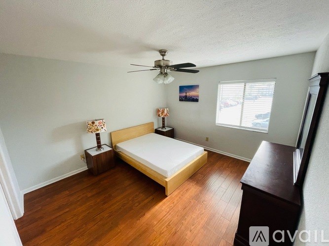 A bedroom with a bed, a ceiling fan, and a window.