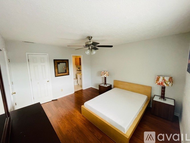 A bedroom with a bed, two lamps, and a ceiling fan.