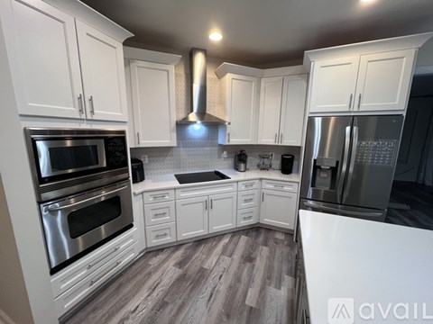 A modern kitchen with white cabinets and stainless steel appliances.