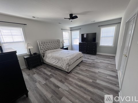 A bedroom with a large bed, a dresser, and a ceiling fan.