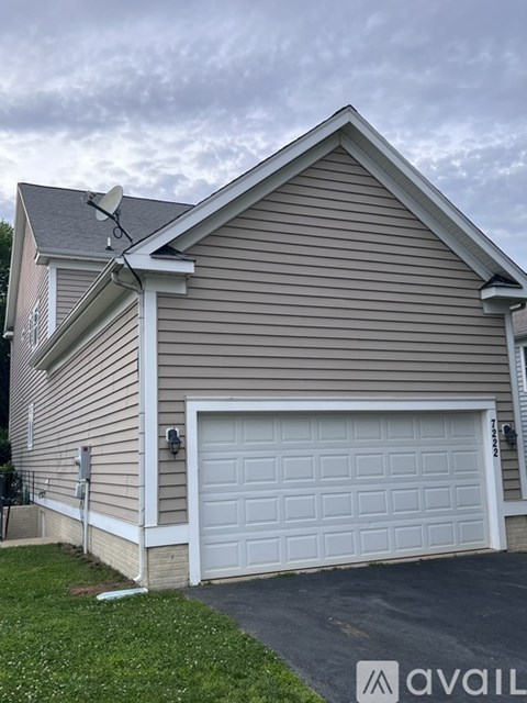 A house with a garage door and a satellite dish on the roof.