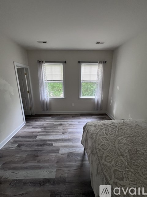 A bedroom with a large bed and a window with blinds.