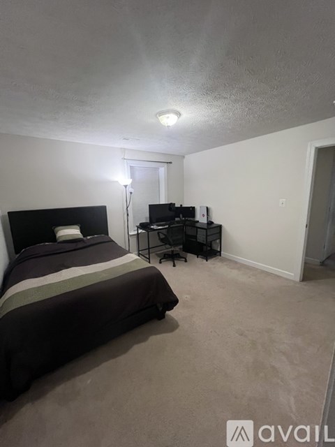 A bedroom with a bed, desk, and chair.