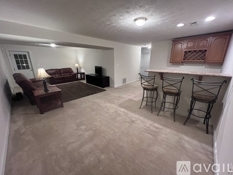 A living room with a couch, chairs, and a television.