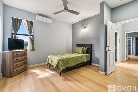 A bedroom with a bed, dresser, and a ceiling fan.