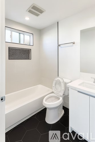 A white toilet in a bathroom with a white cabinet and a white bathtub.