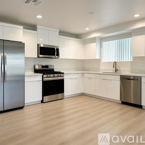 A modern kitchen with white cabinets and stainless steel appliances.