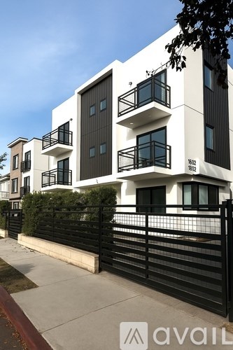 A modern two-story building with balconies and black railings.