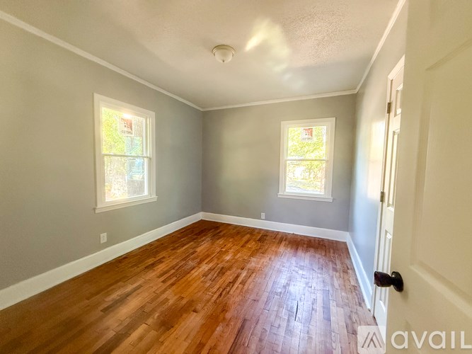 A room with wooden floors and two windows.
