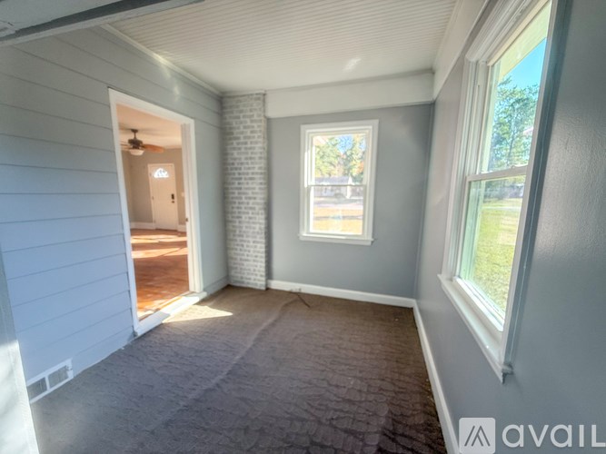 A room with a carpeted floor and a window showing daylight outside.