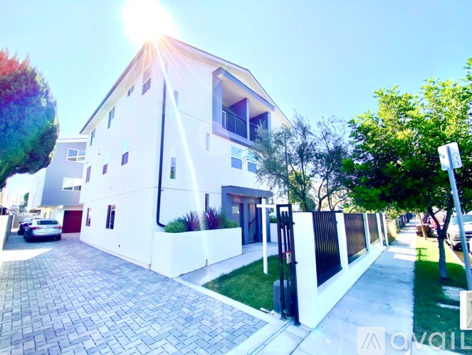 A white house with a black gate and a driveway.