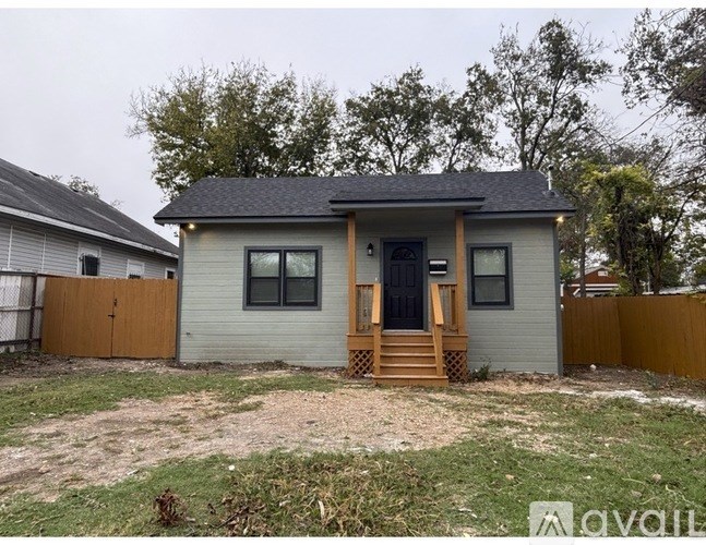 A small house with a porch and a brown fence.