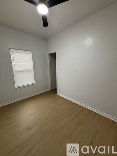 A room with a ceiling fan and wooden flooring.