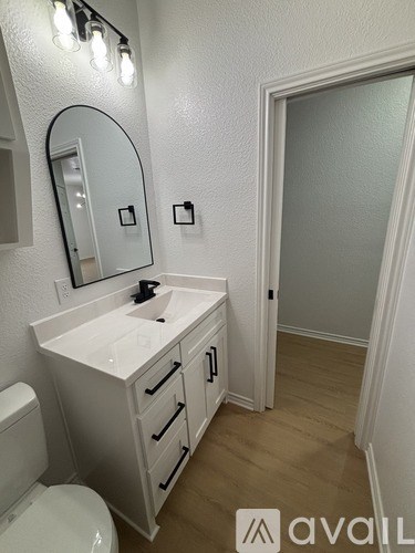 A bathroom with a toilet, sink, mirror and light switches.