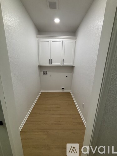 A narrow hallway with wooden floors and white walls.