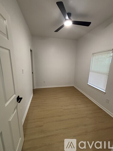 A room with a ceiling fan and wooden flooring.