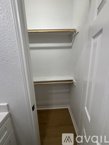 A white closet with a wooden shelf and a door.