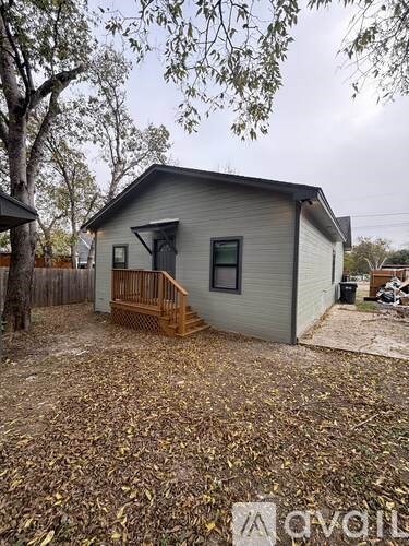 A small house with a grey roof and a brown porch.