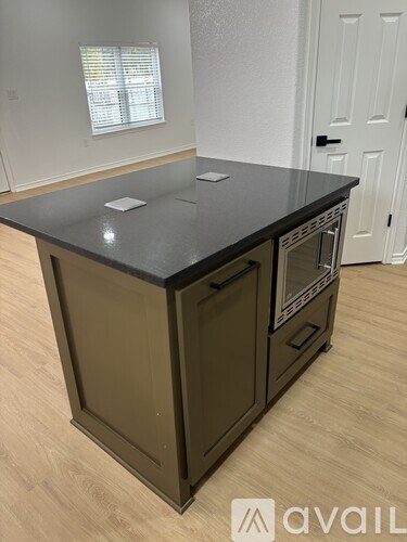 A kitchen island with a black countertop and wooden cabinets.
