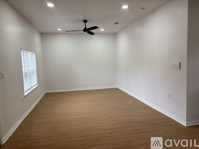 A room with a ceiling fan and wooden flooring.